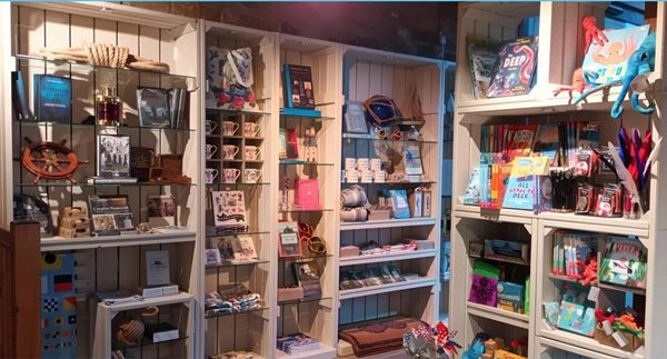 Photo of the Galley gift shop, with colourful maritime-themed products on pale green wooden shelving.